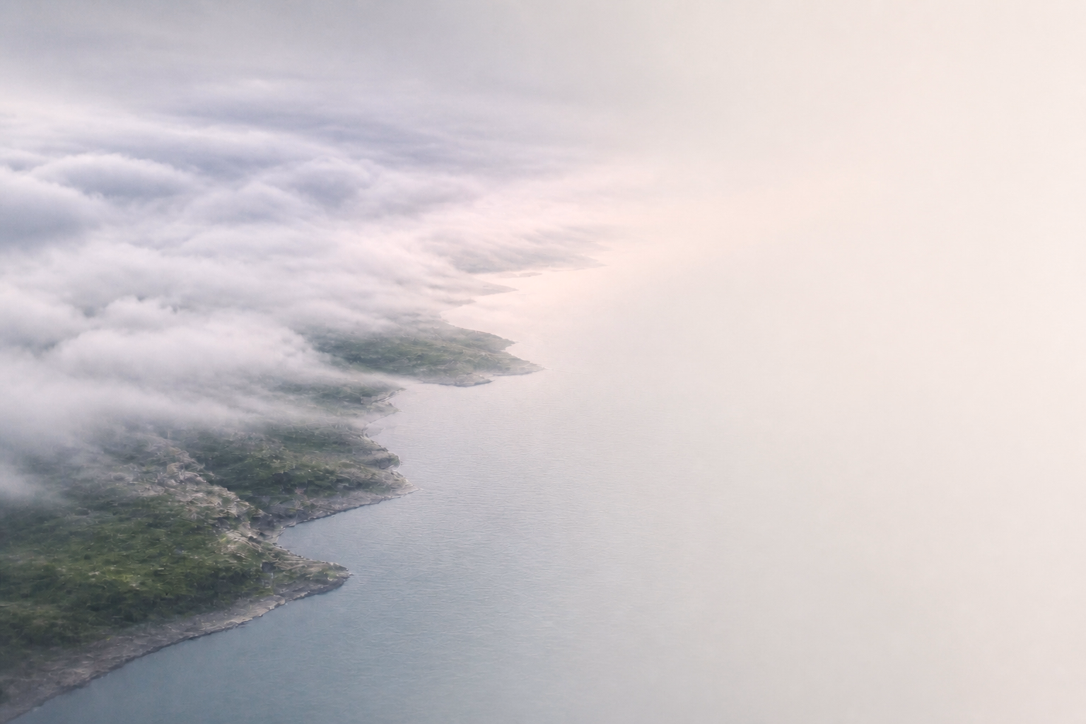 Low cloud moves over a quiet northern coastline.